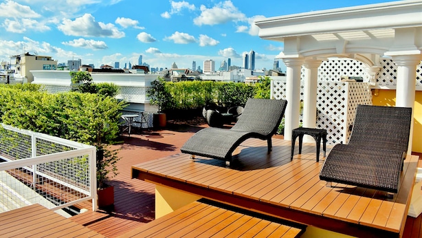 A rooftop terrace with wooden flooring, two lounge chairs, a small table, and a white pergola. - Siri Oriental Bangkok Hotel (Bangkok)