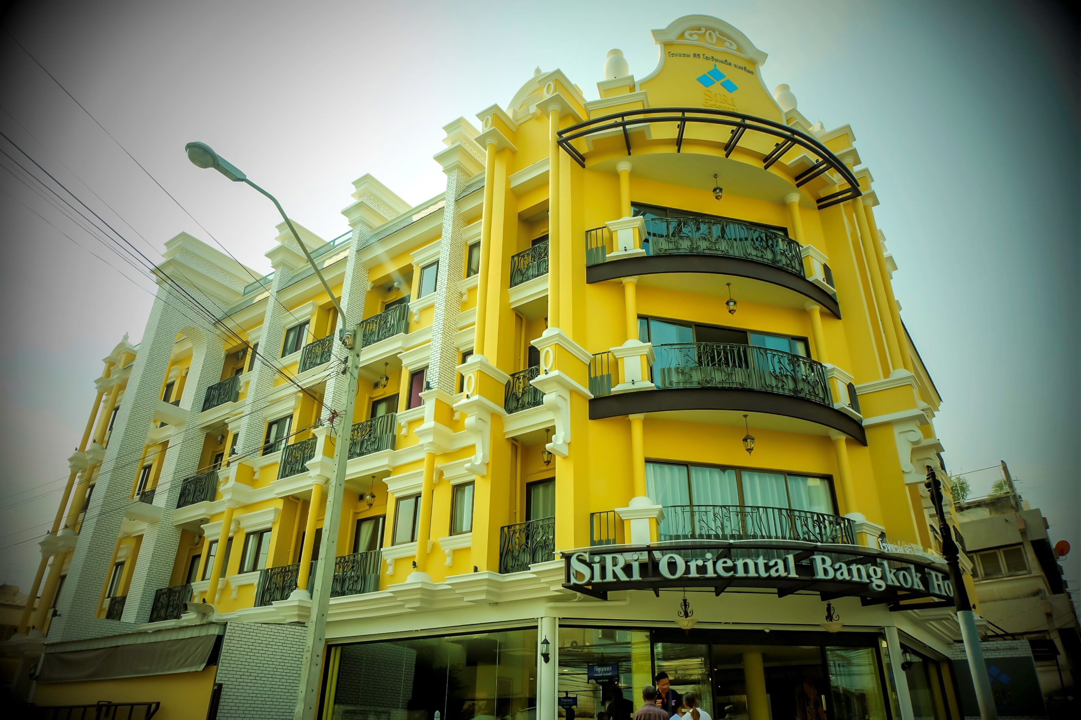 A multi-story building with balconies and a sign for "SRT Oriental Bangkok Hotel".