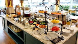A buffet setup with various food items, a coffee station, and a television screen in the background. - Siri Oriental Bangkok Hotel (Bangkok)