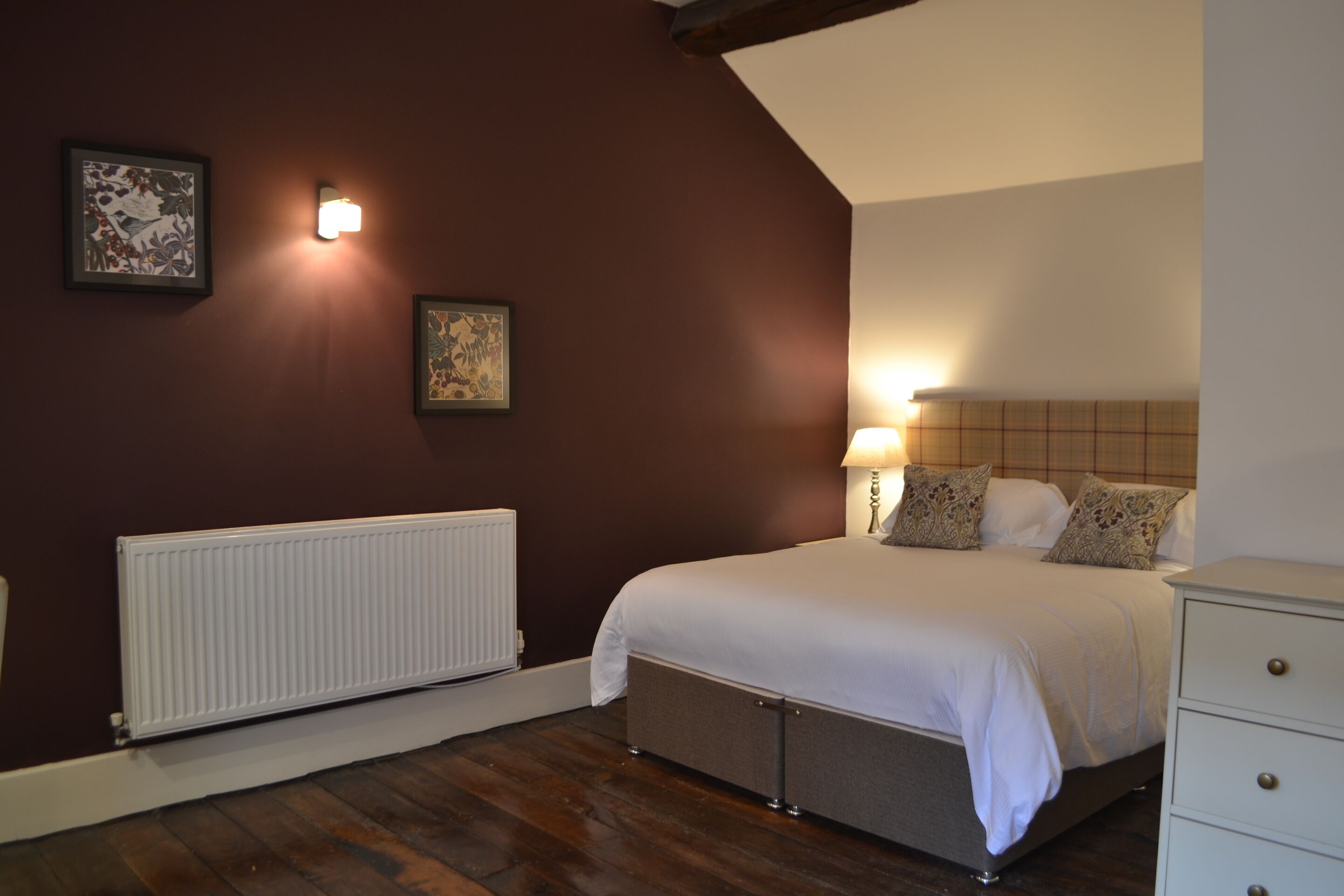 Een slaapkamer met een bed, nachtkastje, lamp en radiator.