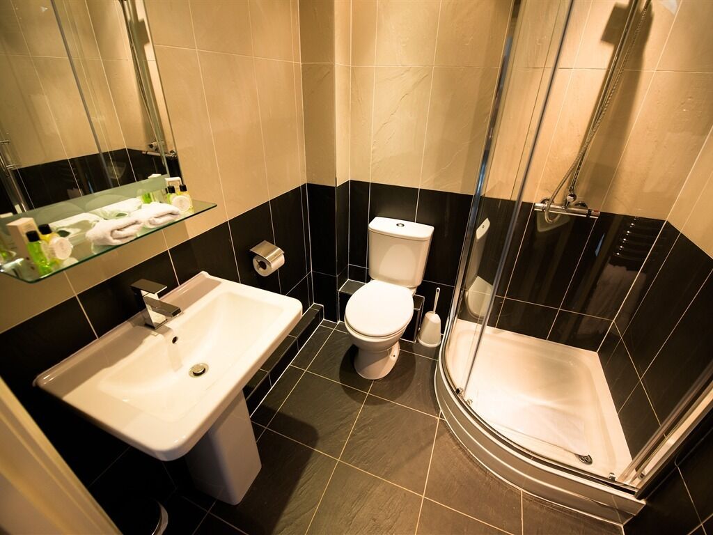 Un bany modern amb dutxa envidriada, un lavabo blanc i un vàter.