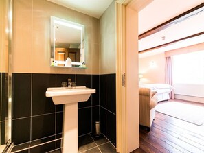 A bathroom with a sink, mirror, and black and beige tiled walls.