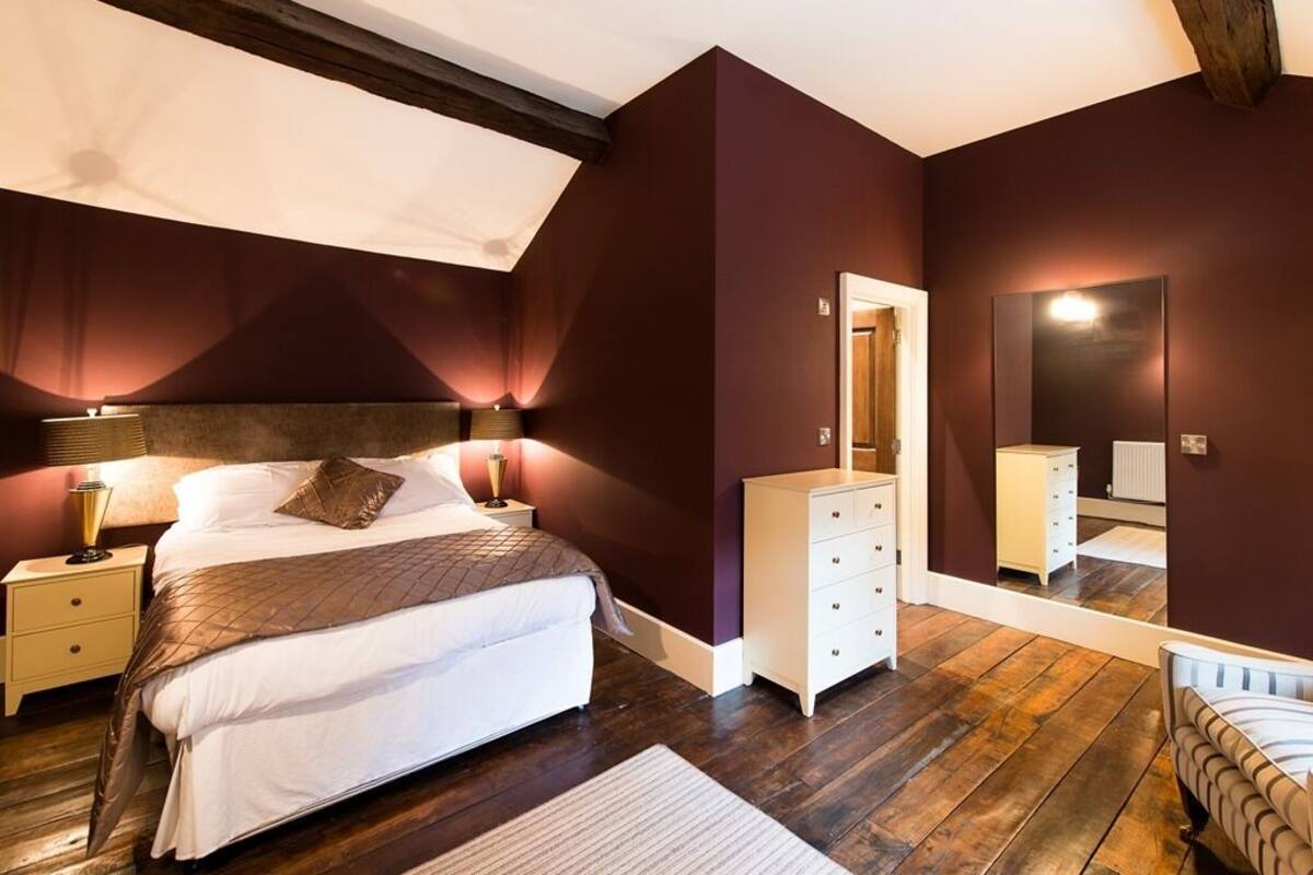 Une chambre à coucher avec un grand lit, une commode, un miroir et une table de chevet.