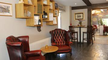 A room with leather armchairs, a wooden bookshelf, and a tiled floor.