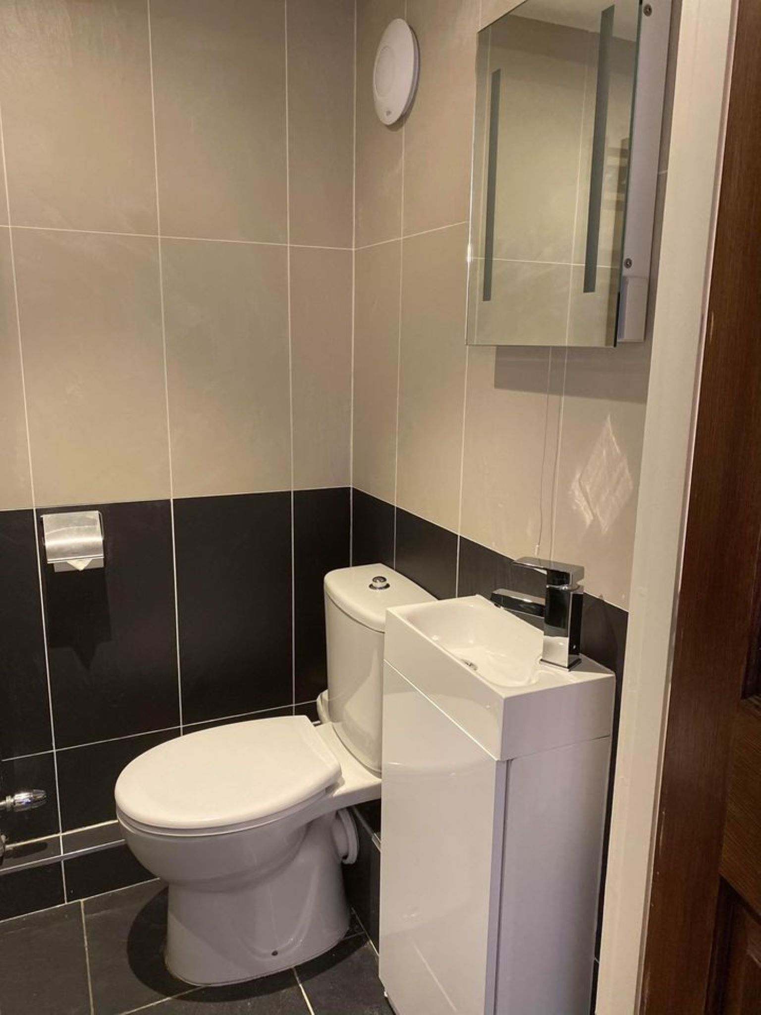 Un bagno moderno con un WC, un lavandino e uno specchio.