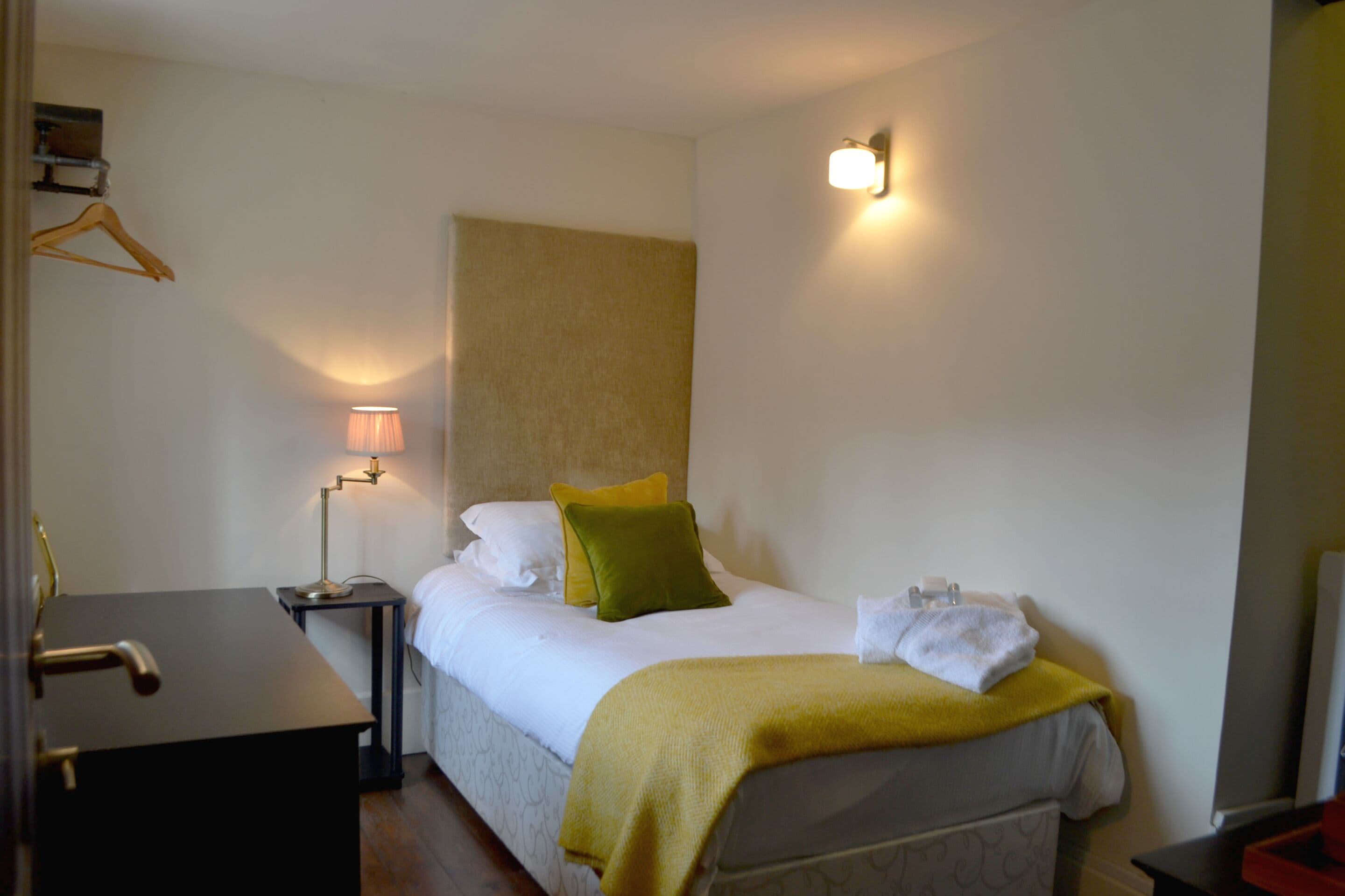 Ein Hotelzimmer mit Bett, Nachttisch, Lampe und einer Garderobe.