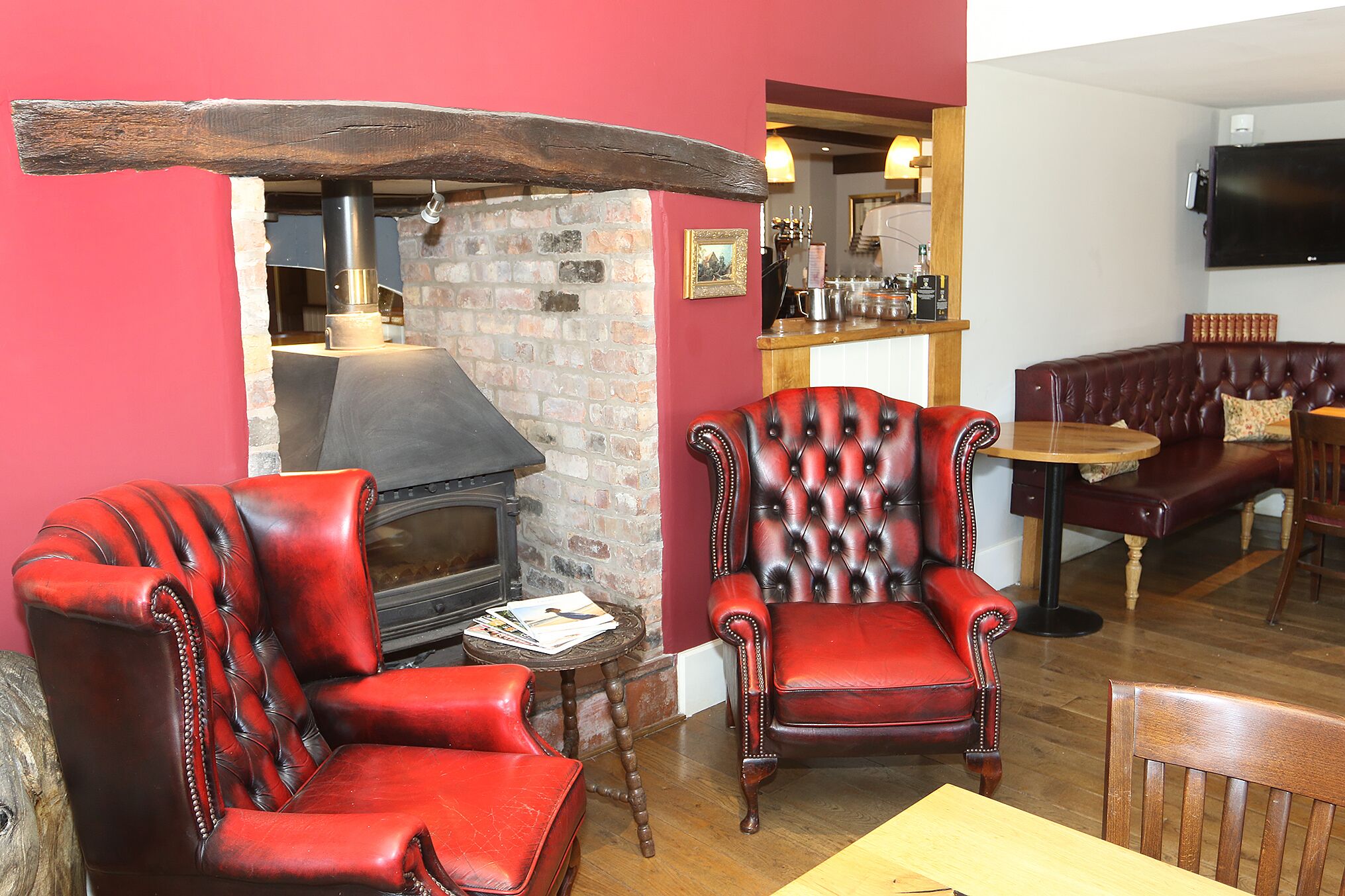 A cozy room with a fireplace, leather armchairs, and a bar area.