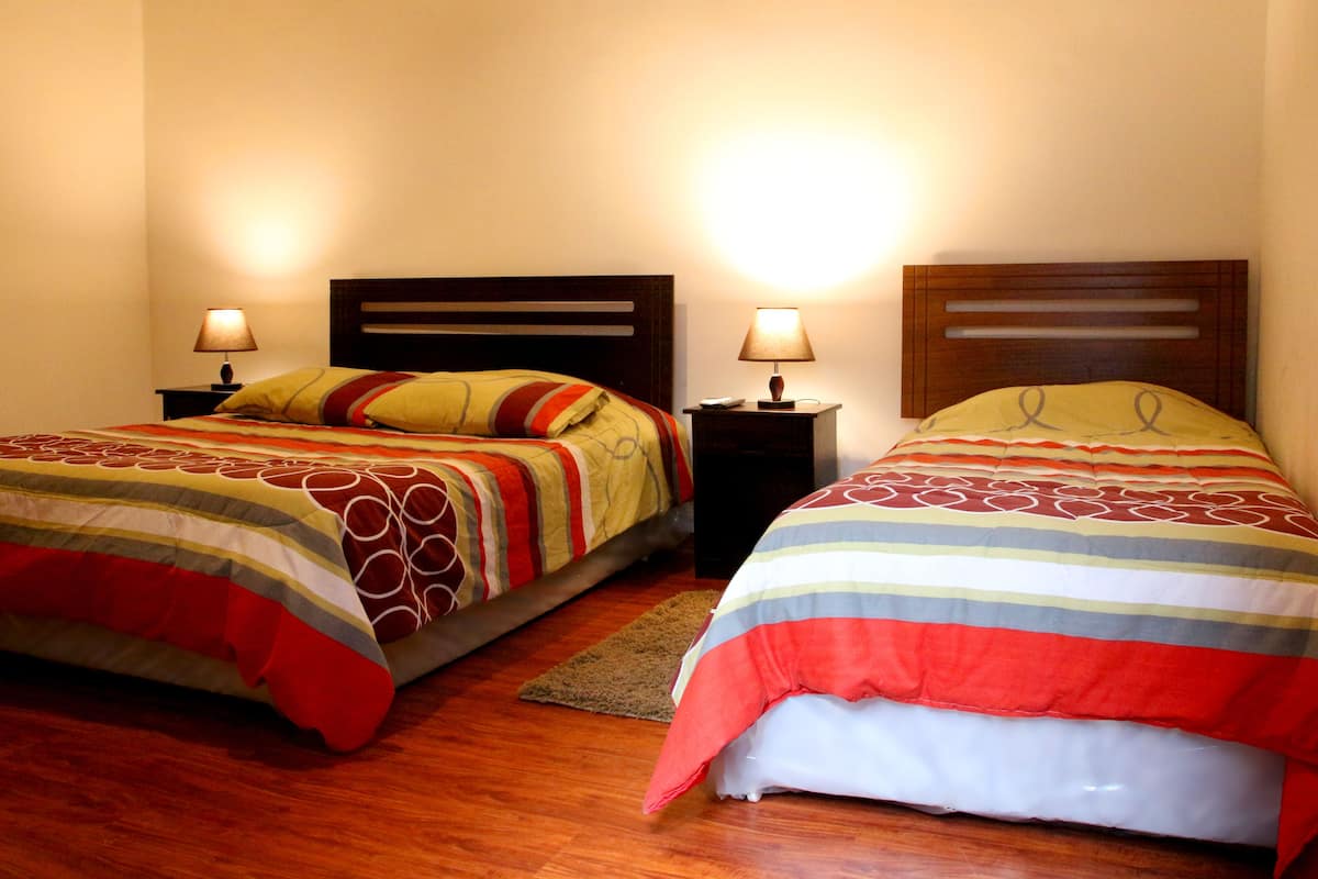 Two single beds with wooden headboards, bedside tables with lamps, and a wooden floor.