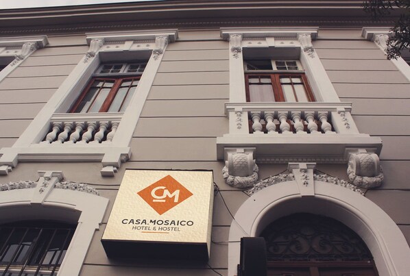Fachada de edificio con un letrero que dice 'CASA MOSAICO HOTEL & HOSTEL'.