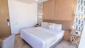 Une chambre d’hôtel moderne avec un grand lit, une armoire en bois, un bureau avec une lampe et une chaise.