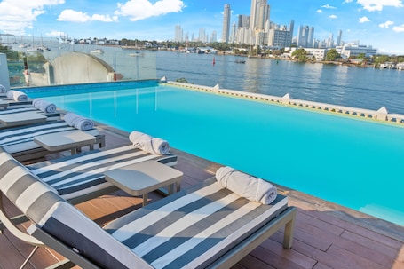 Una piscina al aire libre, sombrillas, sillones reclinables de piscina