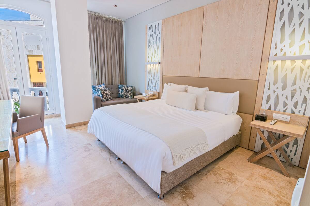 Una habitación de hotel moderna con una cama grande, un escritorio y vistas al exterior.