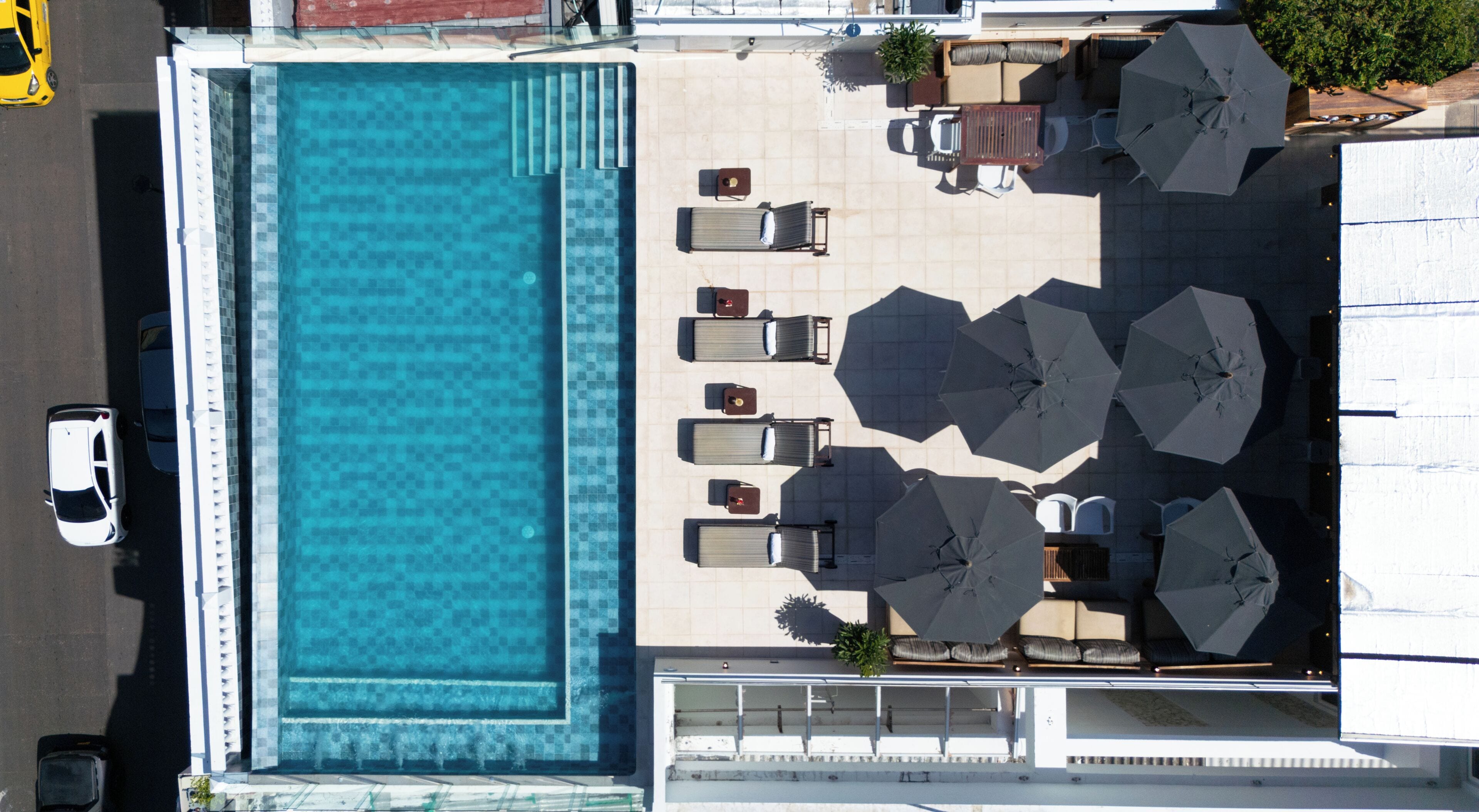 Vista aérea de un área de piscina con tumbonas y sombrillas.
