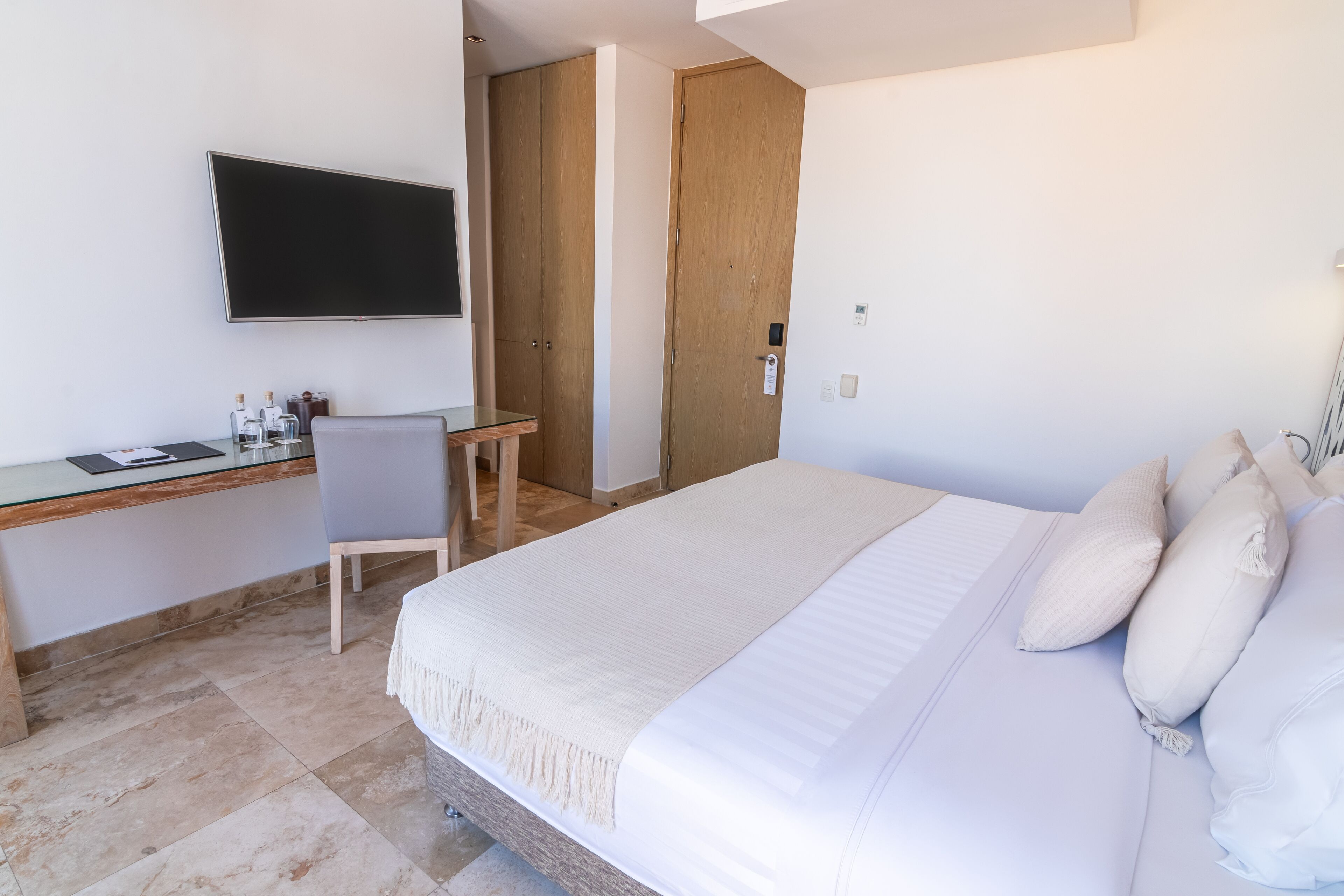 Una habitación de hotel con cama, escritorio, silla y televisión.