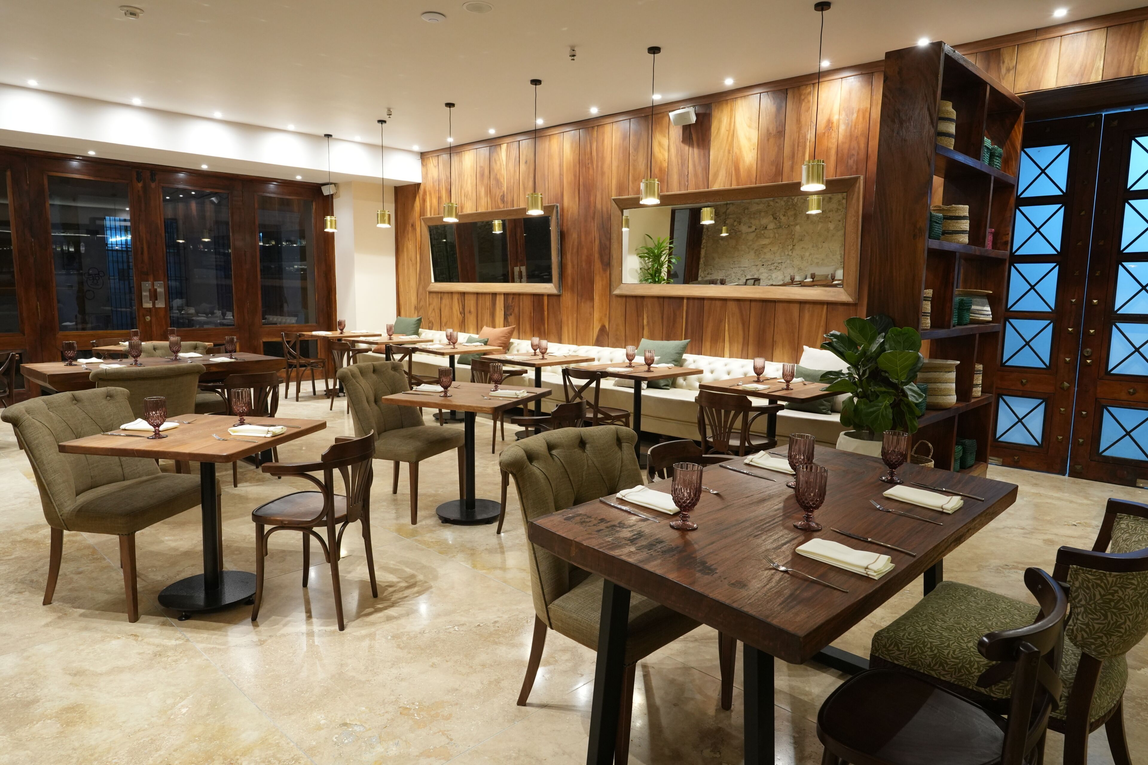 A restaurant with wooden panel walls, multiple dining tables, and chairs.