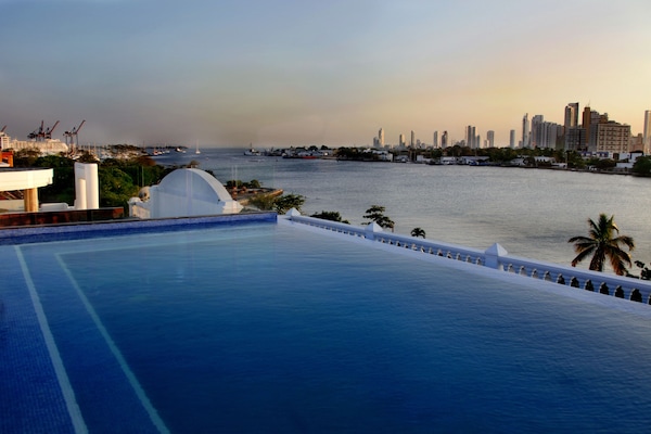 Una piscina al aire libre, sombrillas, sillones reclinables de piscina