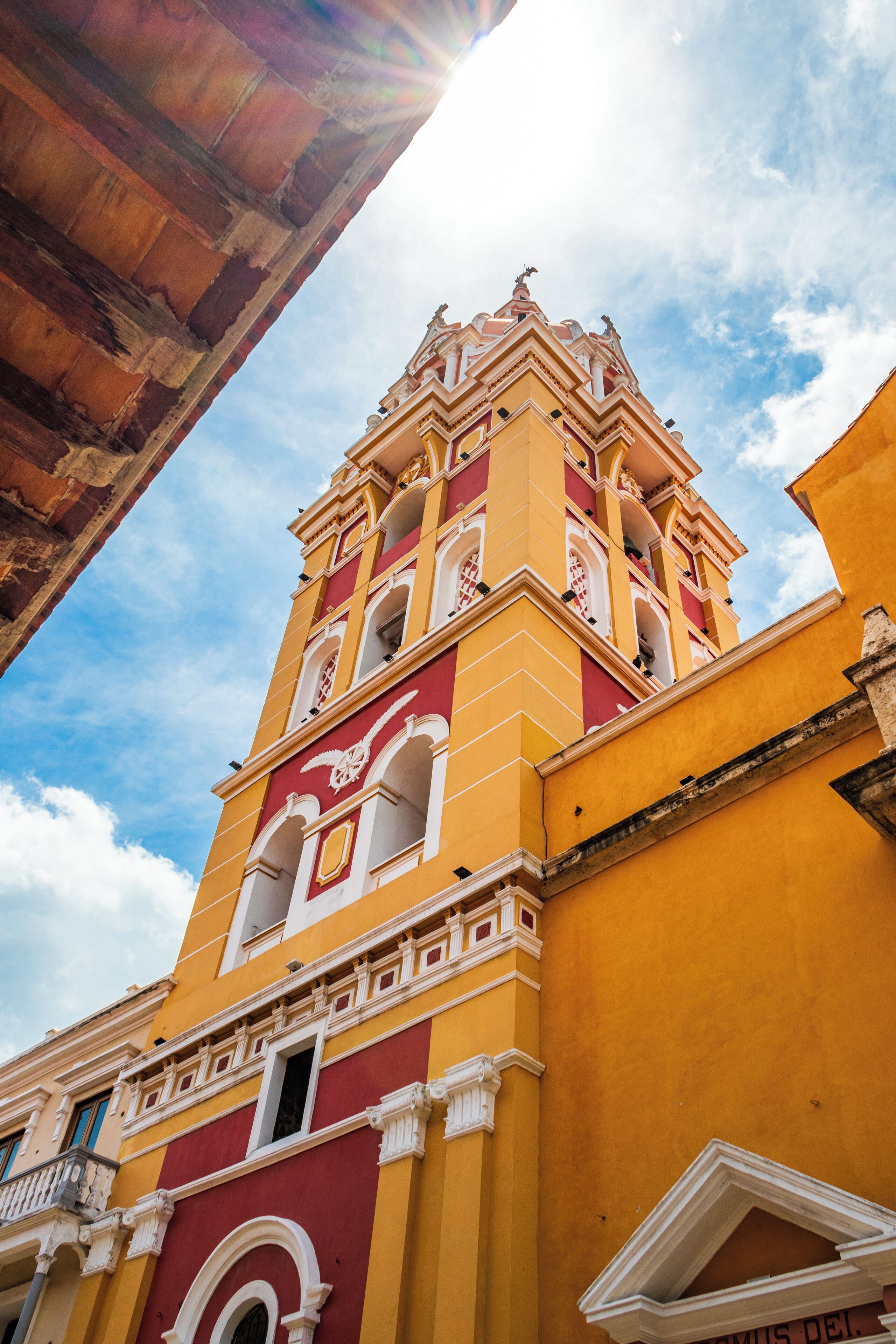 Um edifício amarelo com uma torre de sino vermelha e branca.