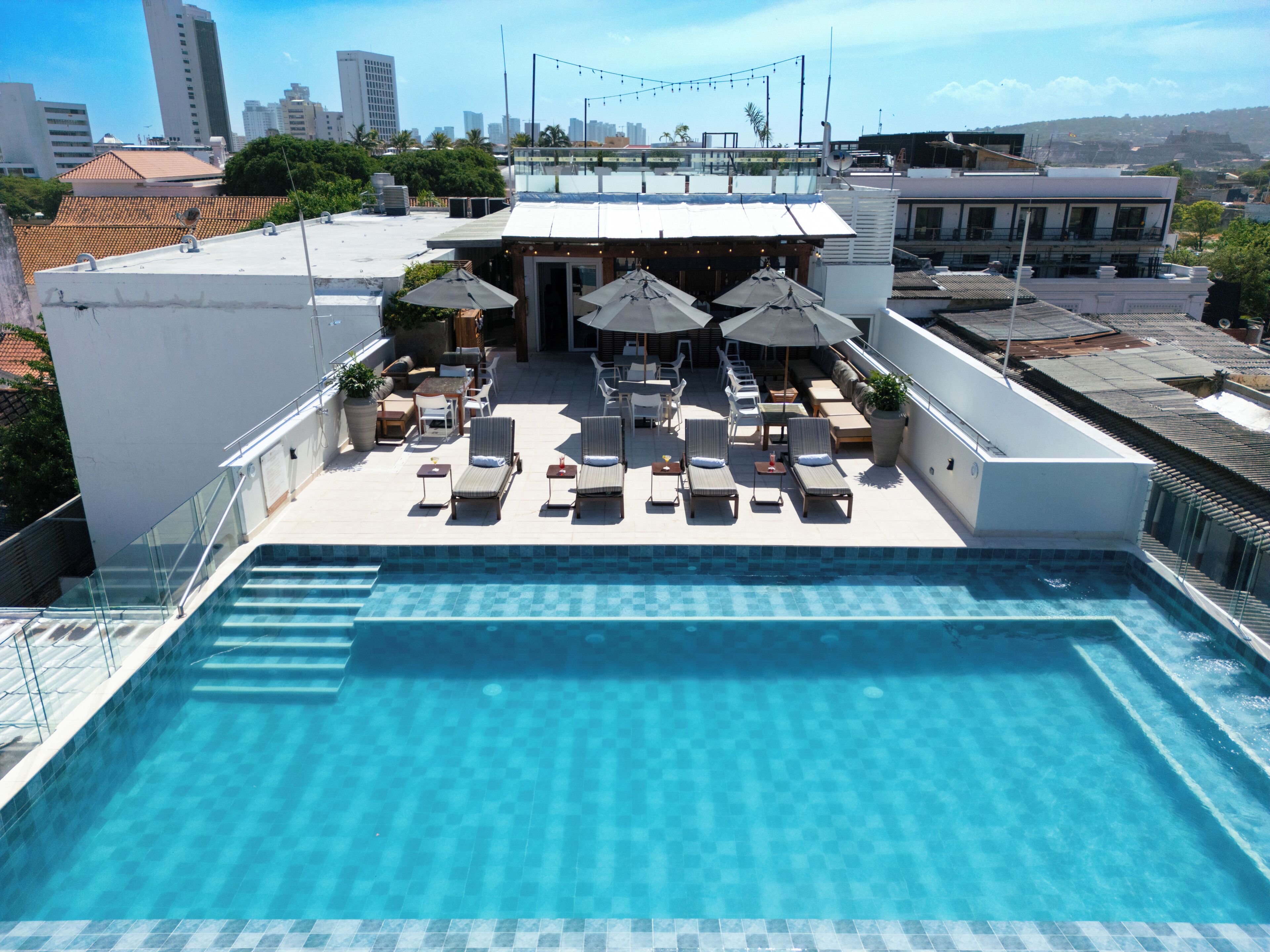 Una piscina al aire libre, sombrillas, sillones reclinables de piscina