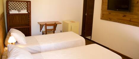 A room with two single beds, a wooden desk, a television mounted on a wooden panel, and a small cabinet.