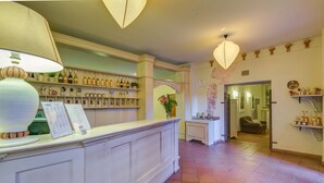 Un espace d’accueil avec un comptoir, des bouteilles de vin et une lampe décorative.