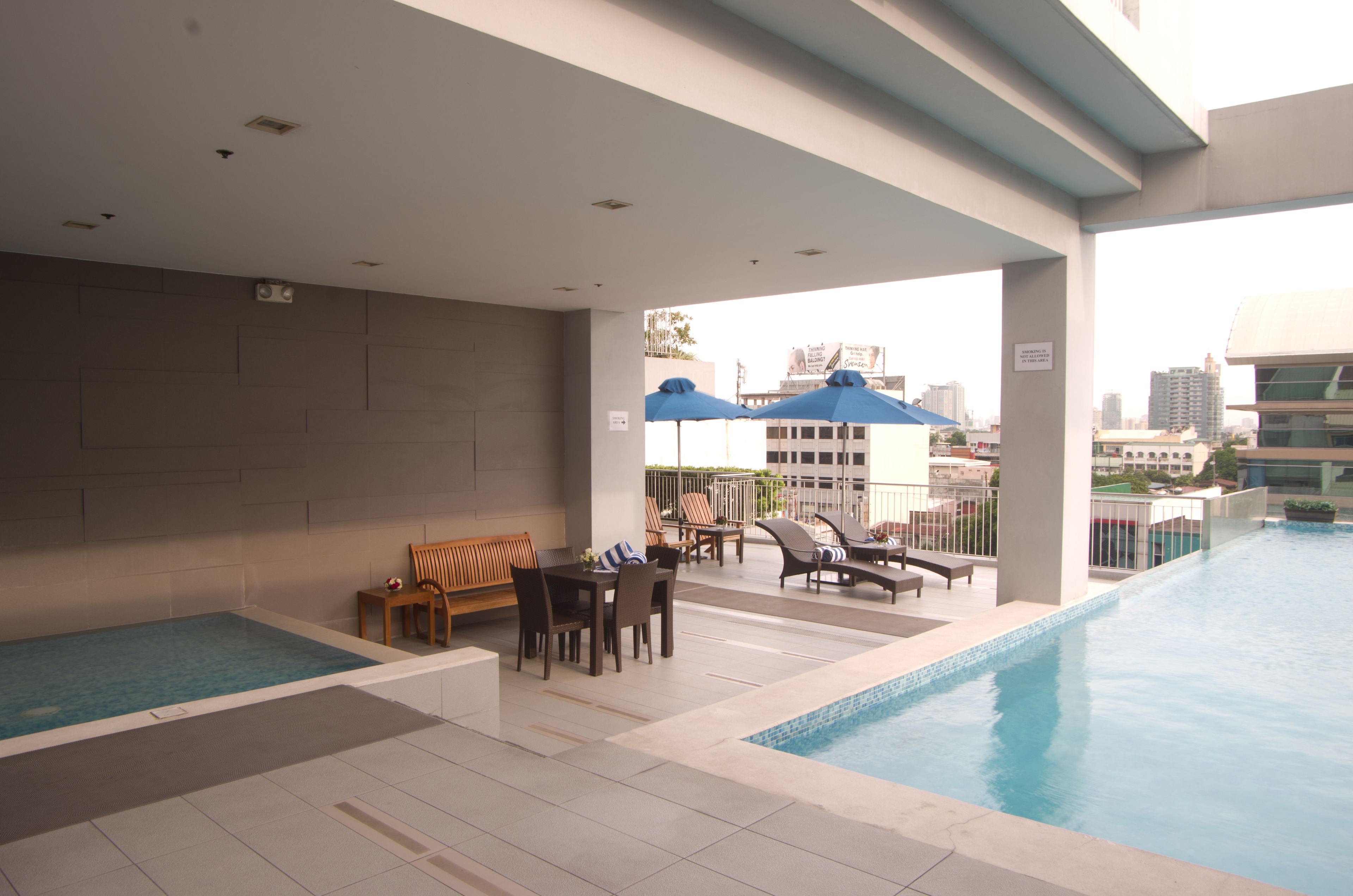 A rooftop pool area with a seating area and lounge chairs.