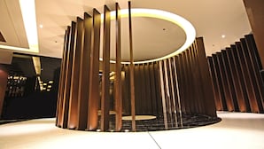 A modern interior with a circular light fixture and vertical wooden slats. - Luxent Hotel (Quezon City)