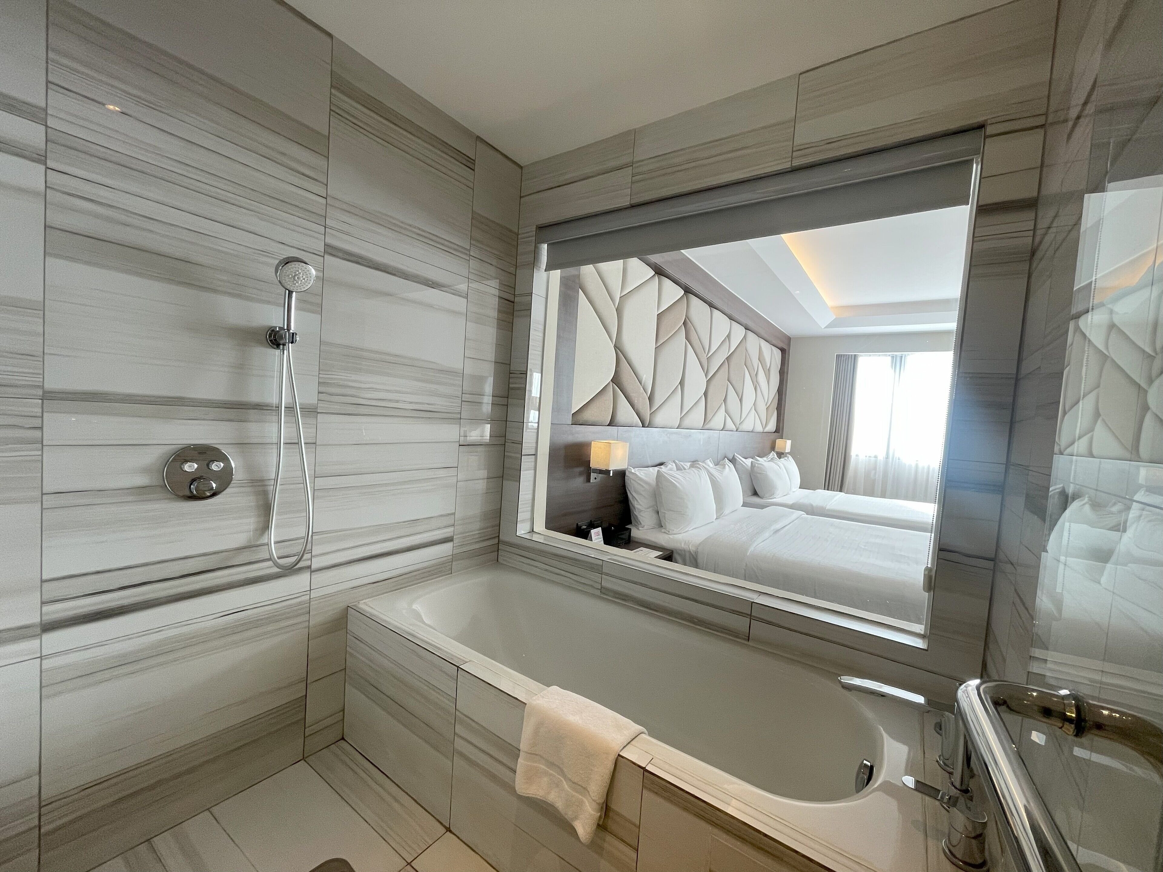 Un baño moderno con un espejo grande, una bañera y una ducha.