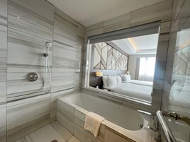 Un baño moderno con un espejo grande, una bañera y una ducha.