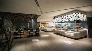 A modern restaurant with a central counter, seating area, and decorative ceiling. - Luxent Hotel (Quezon City)