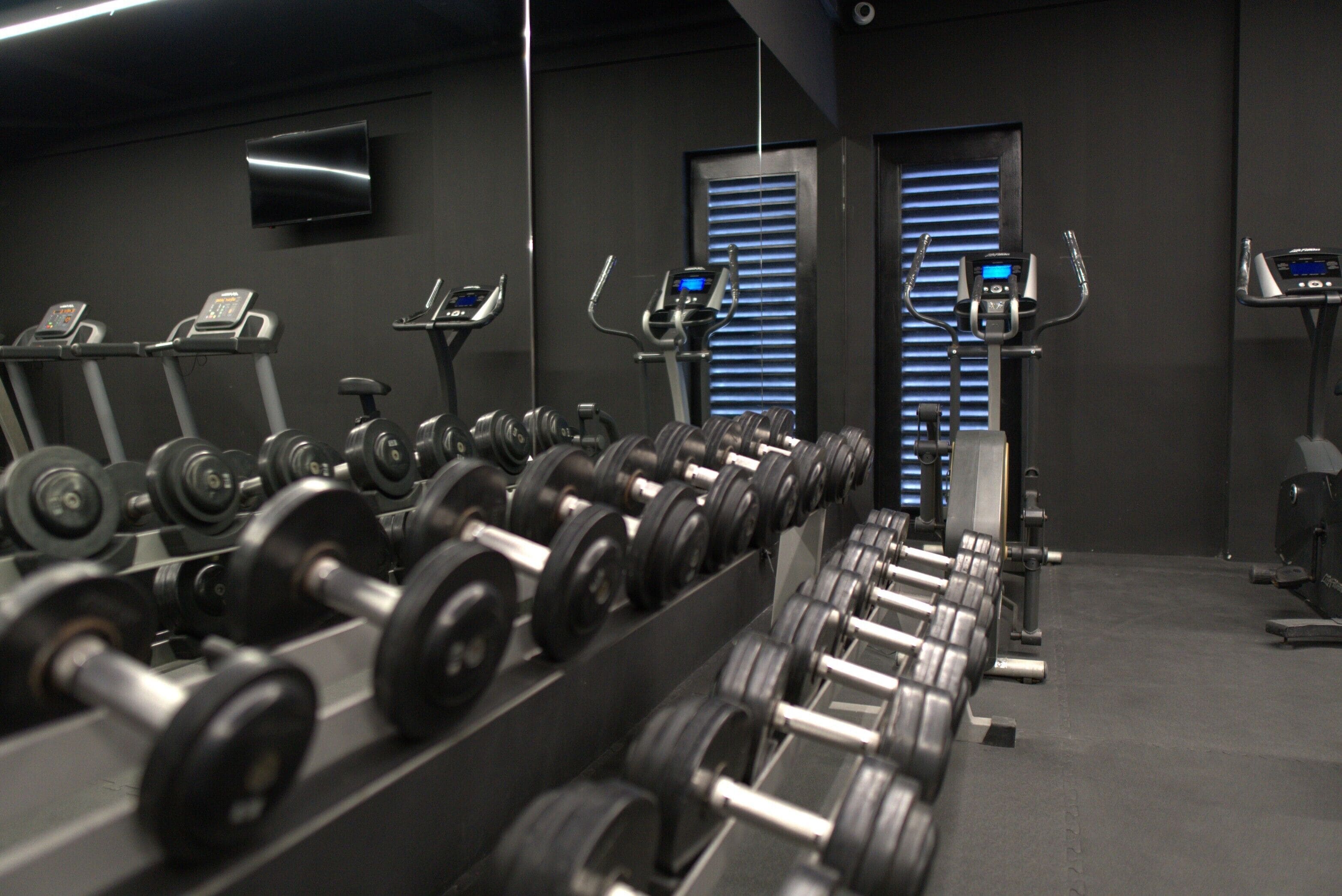 A gym with rows of dumbbells, treadmills, and stationary bikes.