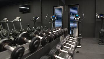 A gym with rows of dumbbells, treadmills, and stationary bikes.