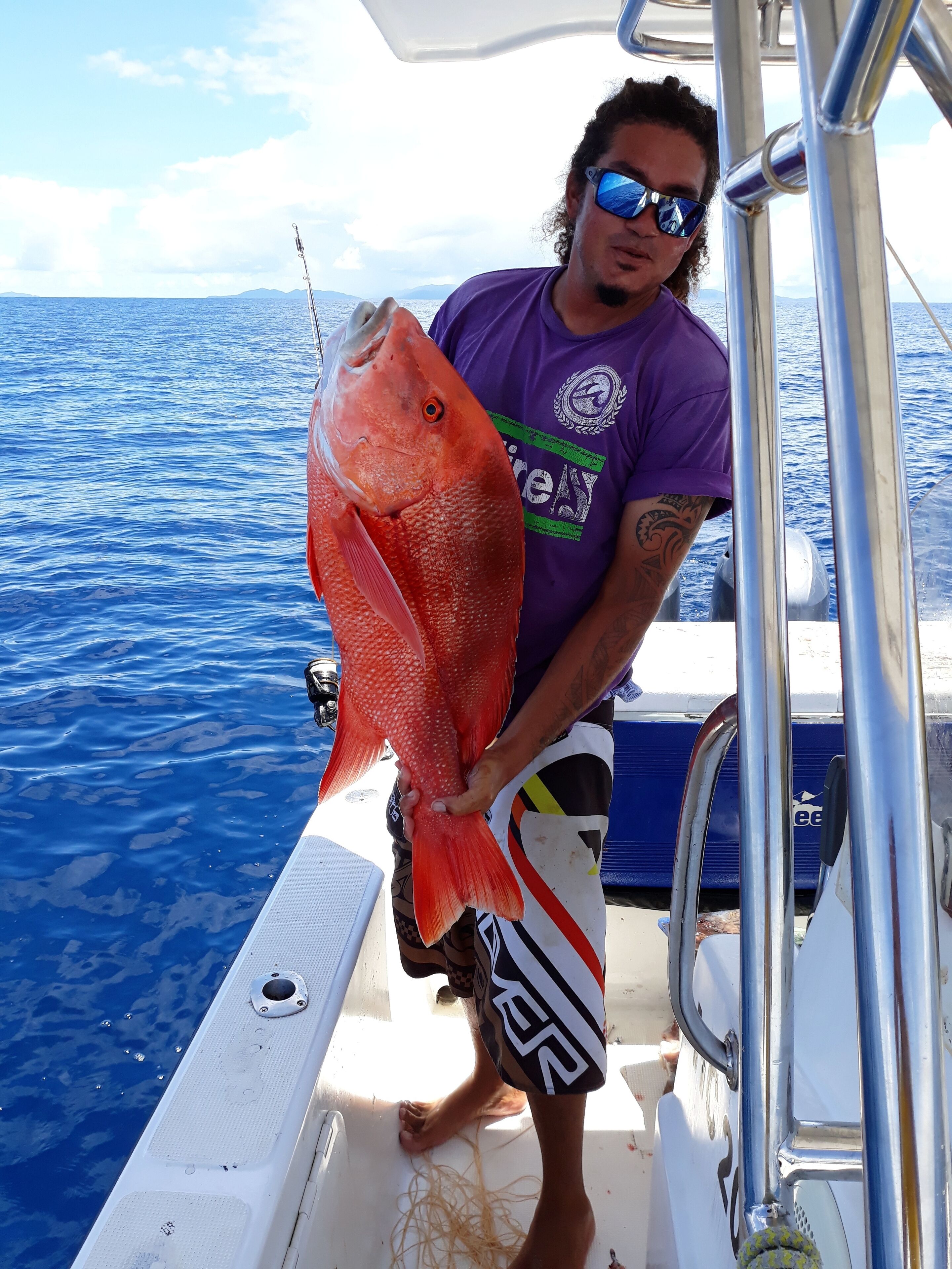 Una persona sostiene un pez rojo grande en un bote.