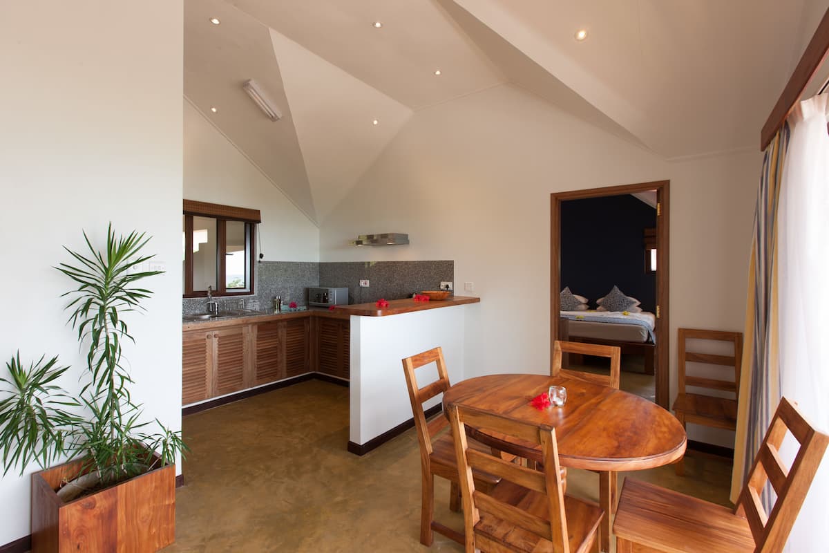 Eine moderne Küche mit Holzschränken, einer zentralen Kochinsel und einem Essbereich mit Holztisch und Stühlen.