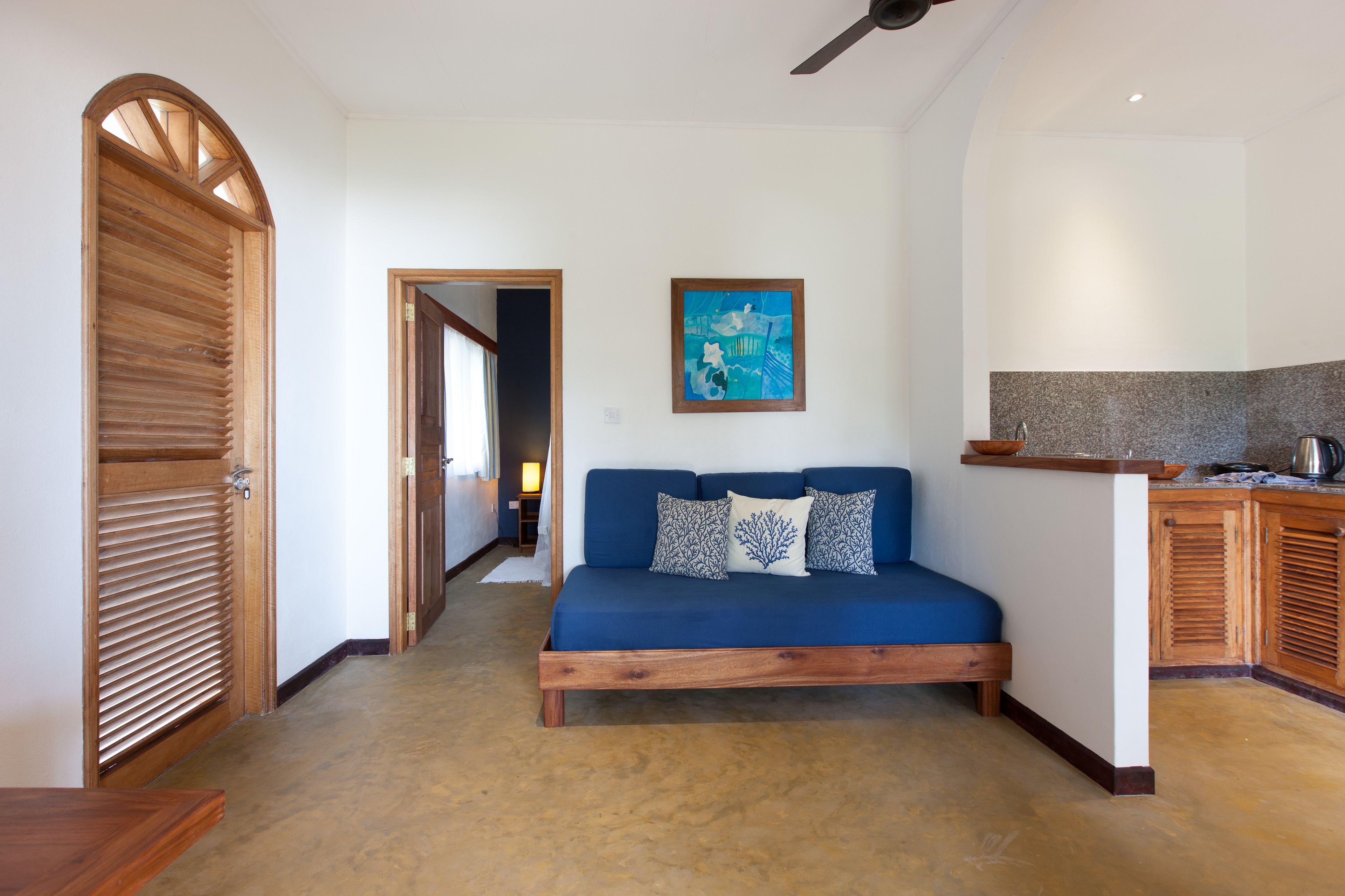 Una habitación con un sofá azul, armarios de madera y un ventilador de techo.