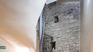 Un escalier avec des murs en pierre et une rampe en métal.