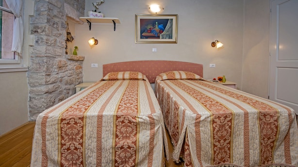 Una habitación con dos camas, una pared de piedra, un cuadro y una alfombra.