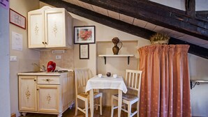 Une petite cuisine accueillante, avec des meubles en bois, une table à manger et une bouilloire rouge.