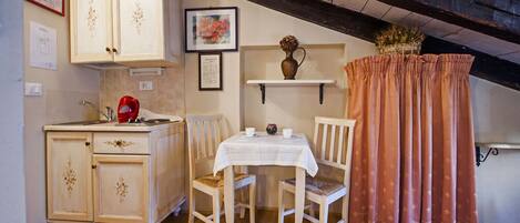 Une petite cuisine accueillante, avec des meubles en bois, une table à manger et une bouilloire rouge.