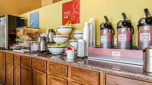 A breakfast bar with coffee dispensers, bowls of fruit, and a cereal box. - Comfort Inn & Suites Meriden East (Meriden)