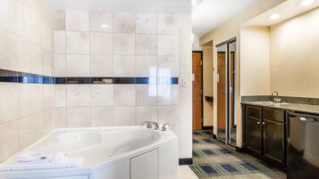 A modern bathroom with a large bathtub, a sink, and a tiled floor.