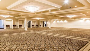 A large, well-lit room with patterned carpet, multiple doors, and chandeliers. - Comfort Inn & Suites Meriden East (Meriden)