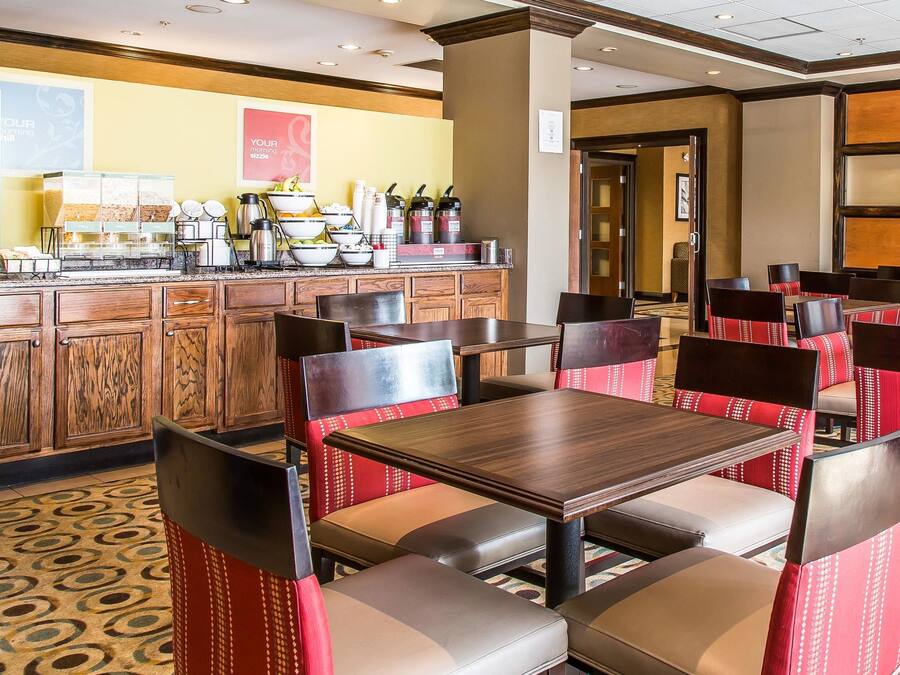 A hotel dining area with a buffet setup, wooden cabinets, and red upholstered chairs.