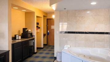 A hotel bathroom with a bathtub, a coffee machine, and a trash can.