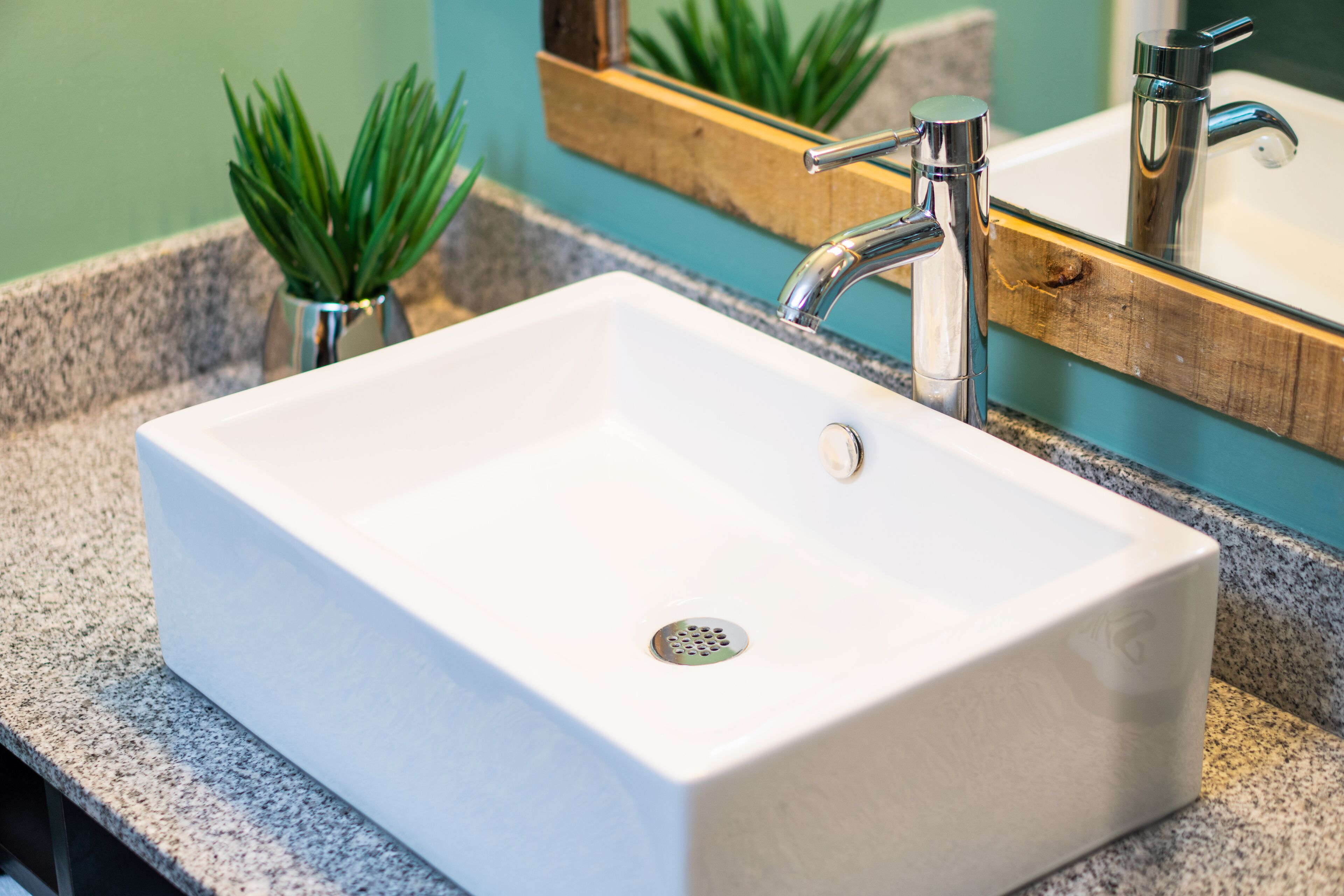 Un lavamanos de baño blanco rectangular con un grifo cromado, sobre una encimera de granito.