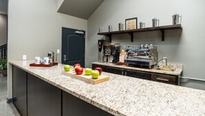 A kitchen with a granite countertop, a coffee machine, and a sink. - The Hotel Sync (Bowling Green)