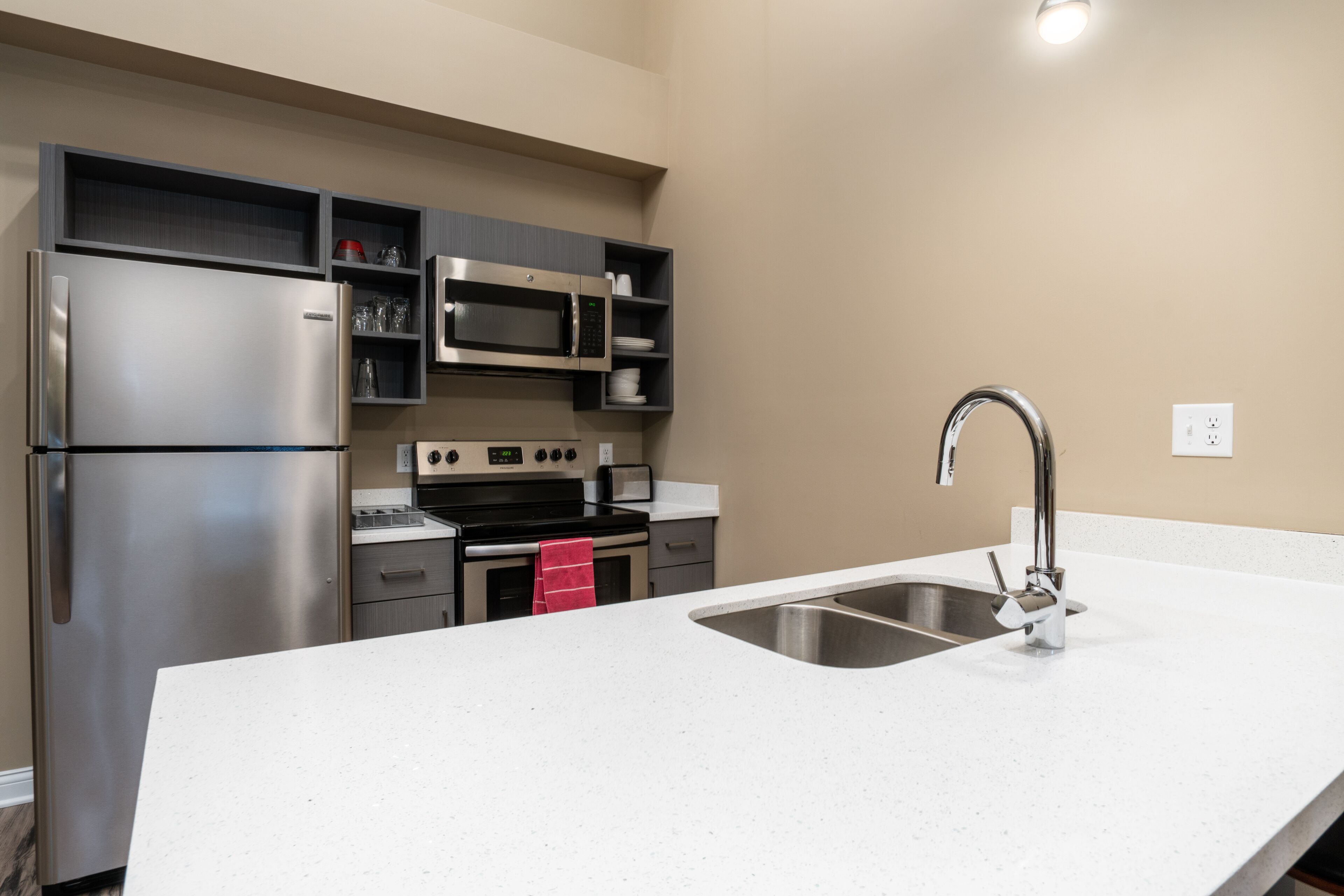 A modern kitchen with stainless steel appliances, a white countertop, and a built-in microwave.