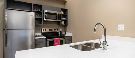 A modern kitchen with stainless steel appliances, a white countertop, and a built-in microwave.