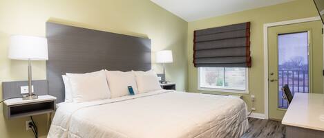 A neatly arranged bedroom with a large bed, bedside tables, a nightstand, and a window with blinds.