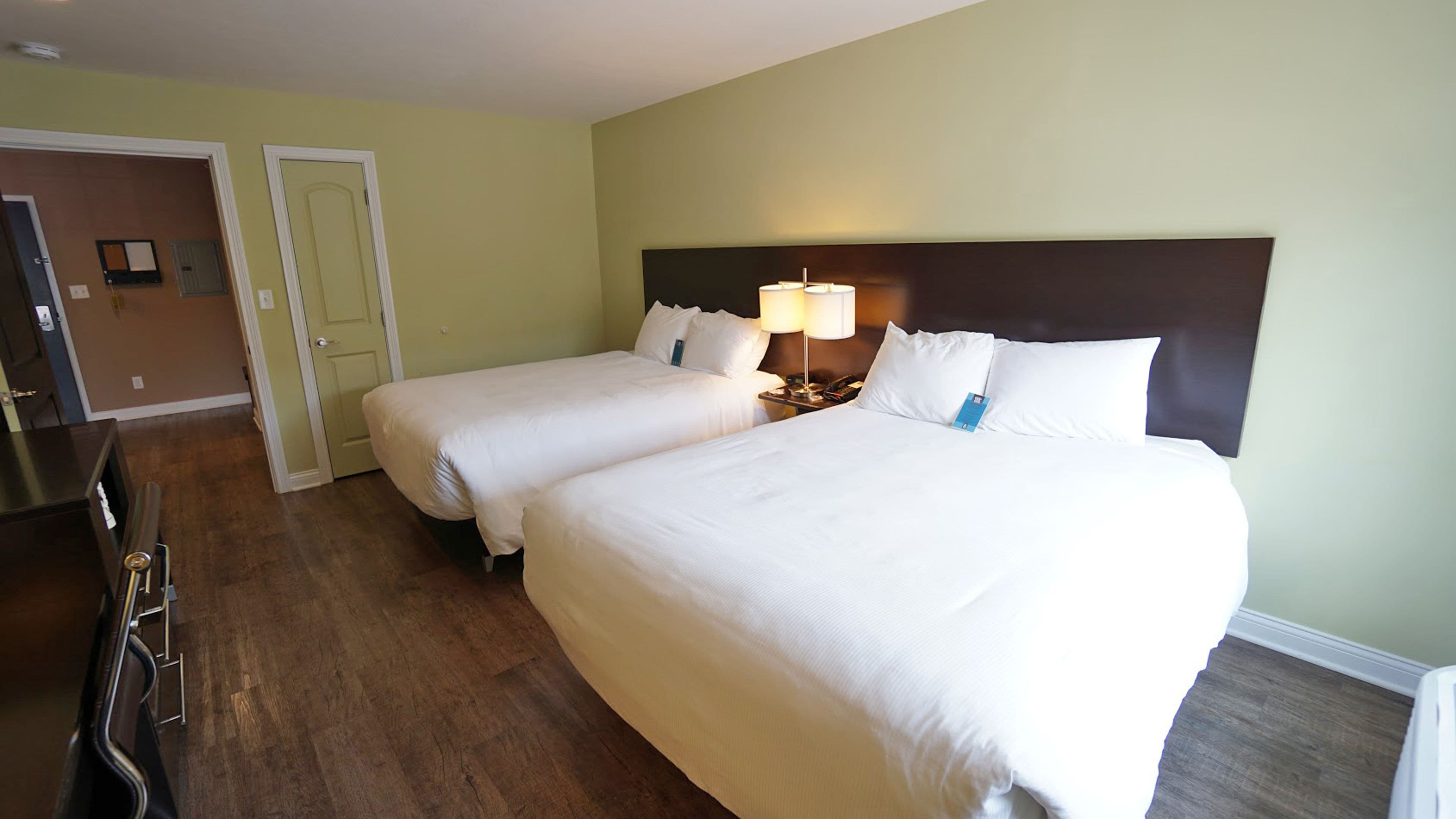 Une chambre d’hôtel avec deux lits, un bureau et une porte donnant sur une salle de bain.