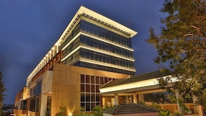 A modern hotel with a multi-story structure, large windows, and a well-lit entrance. -  Mysore County Retreat (Mysore)